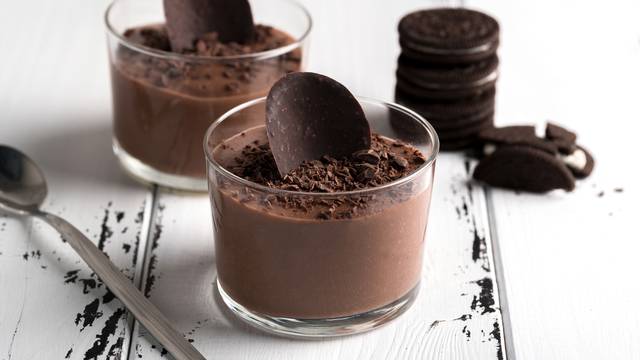 Chocolate mousse in a glasses on a white wood background.