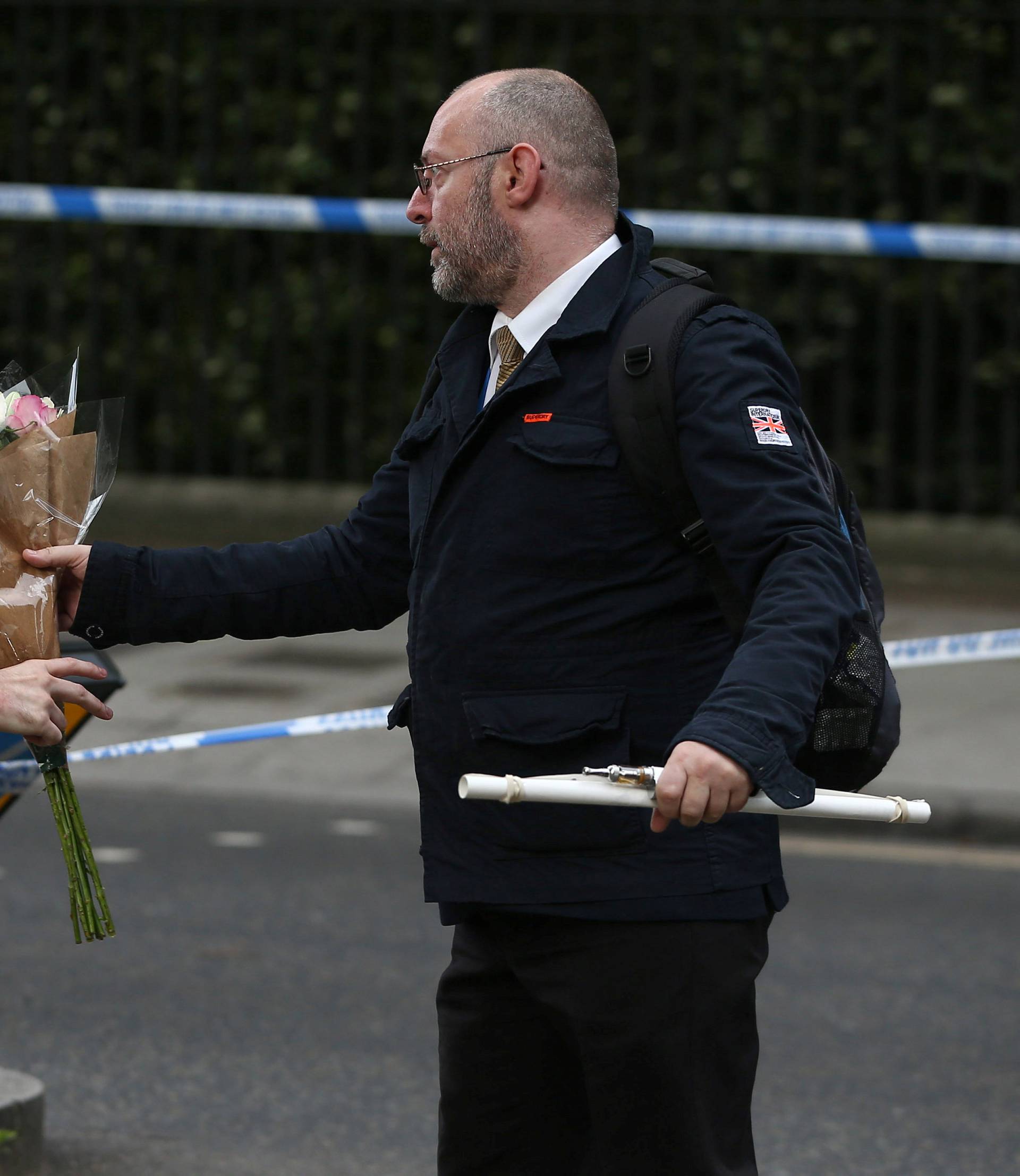 A man gives a police officer a floral tribute after a knife attack in Russell Square in London