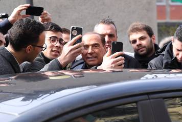Forza Italia party leader Silvio Berlusconi poses for a selfie after casting his vote at a polling station in Milan
