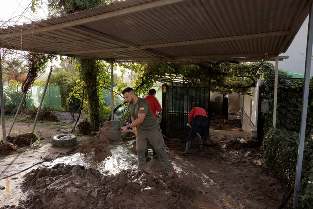 People remove the mud of a house after heavy rains and floods in Alora