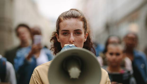 Female,Activist,Protesting,With,Megaphone,During,A,Strike,With,Group