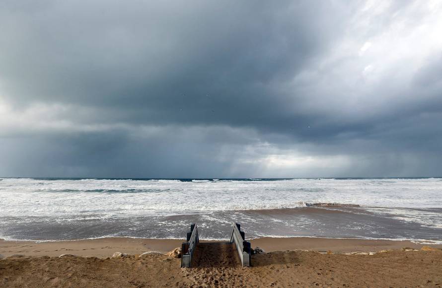 Clouds hang in the sky above the Atlantic ocean as waves from an early winter storm covers the beachfront in Lacanau
