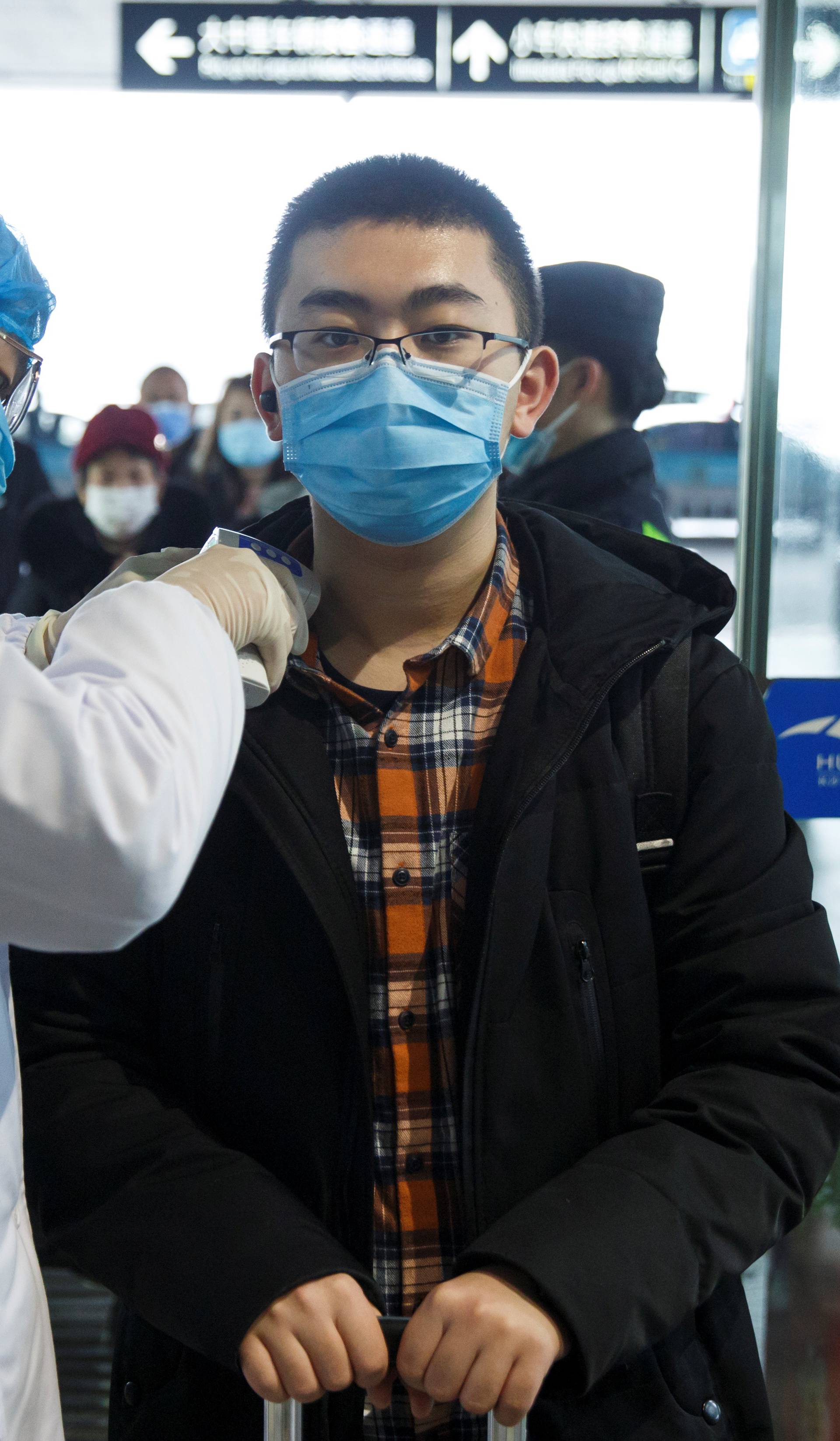 A medical official takes the body temperature of a man at the departure hall of the airport in Changsha