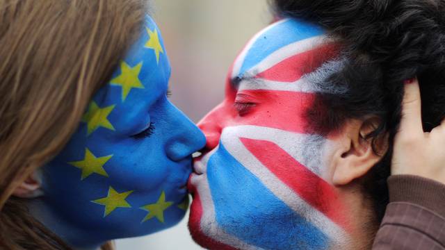 Two activists with the EU flag and Union Jack painted on their faces kiss each other in front of Brandenburg Gate to protest against Brexit in Berlin