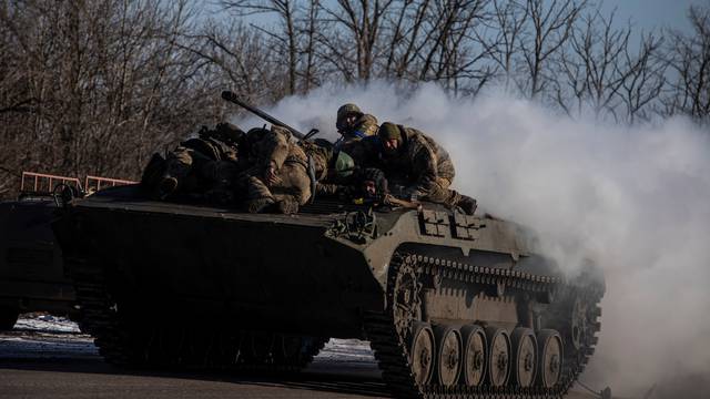 Ukrainian service members ride atop of a BMP-2 infantry fighting vehicle near a frontline in Donetsk region