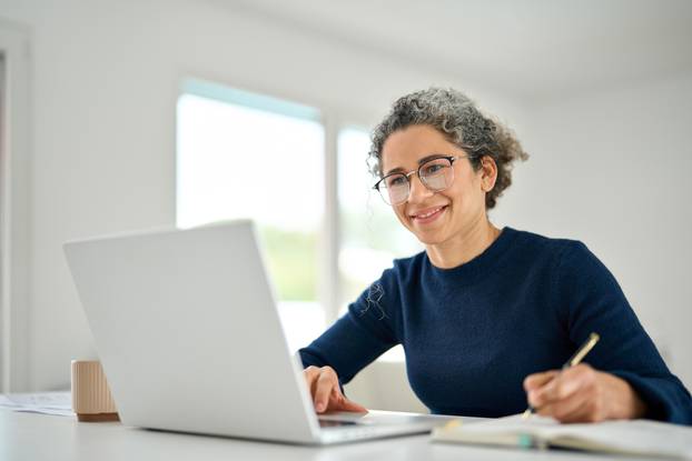 Happy,Middle,Aged,Woman,Sitting,At,Table,At,Home,Office