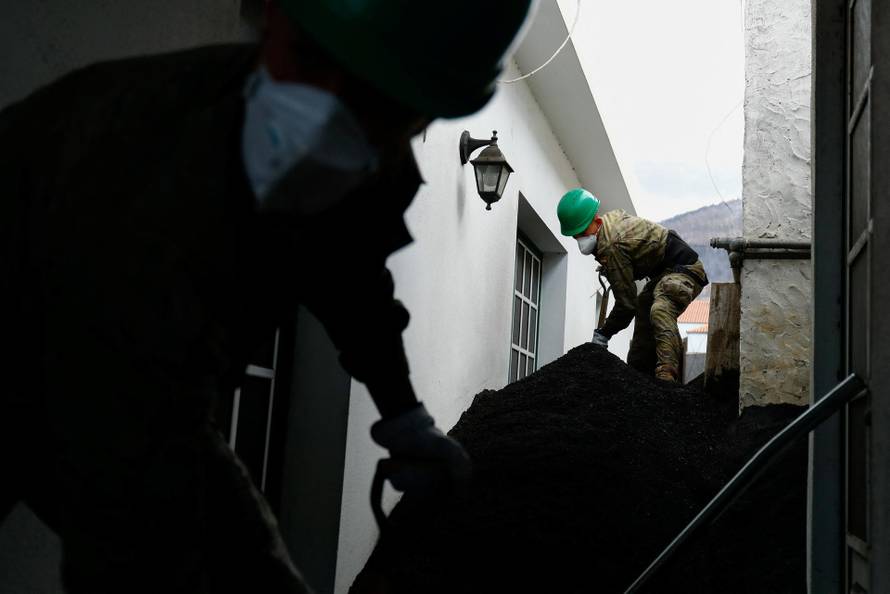 Spanish military clean the ash from the Cumbre Vieja volcano that surrounds a house in Las Manchas