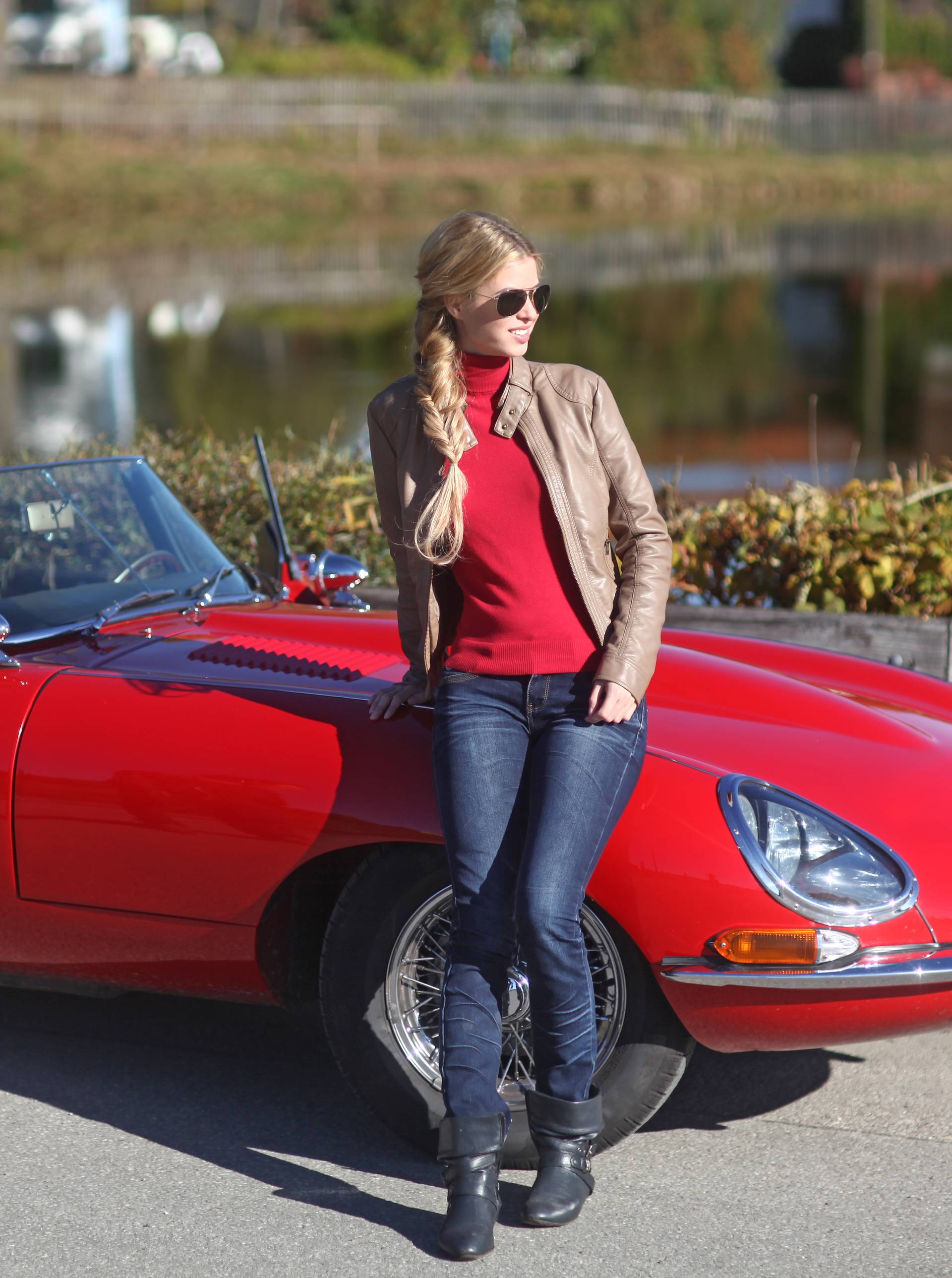 Mature man and young woman leaning against red sports car