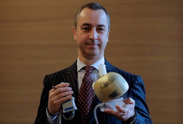 Carmat Chief Executive Officer Stephane Piat holds an artificial heart as he poses after the company