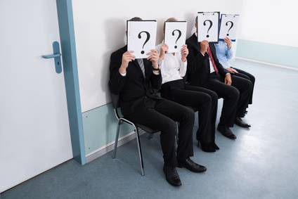 Businesspeople Hiding Behind Question Mark Sign