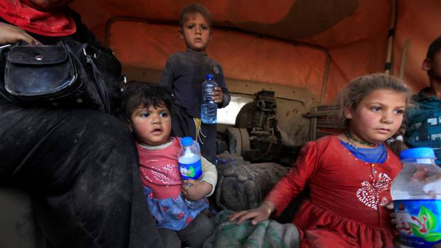 Displaced people who are fleeing from clashes sit in a military vehicle in Qayyarah, during an operation to attack Islamic State militants in Mosul