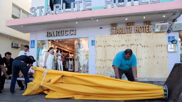 Workers remove umbrellas at Caffe Milano in anticipation of Hurricane Matthew in South Beach