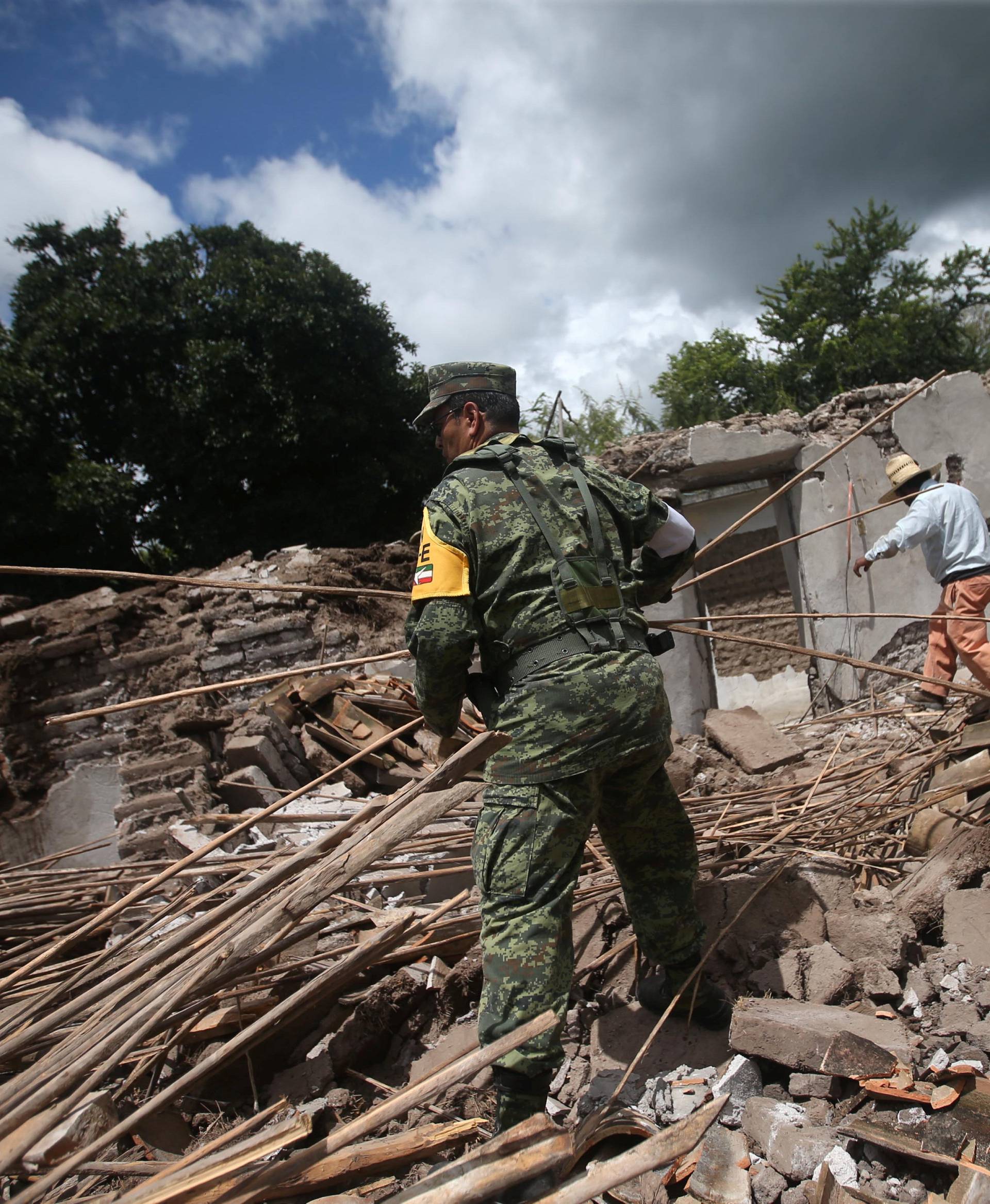 A soldier and a resident clear rubble from a destroyed house after an earthquake in San Juan Pilcaya, at the epicenter zone