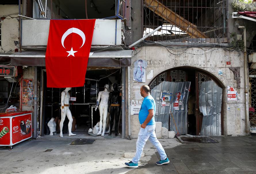 A man walks past by a damaged shop near the scene of Tuesday's car bomb attack on a police bus, in Istanbul