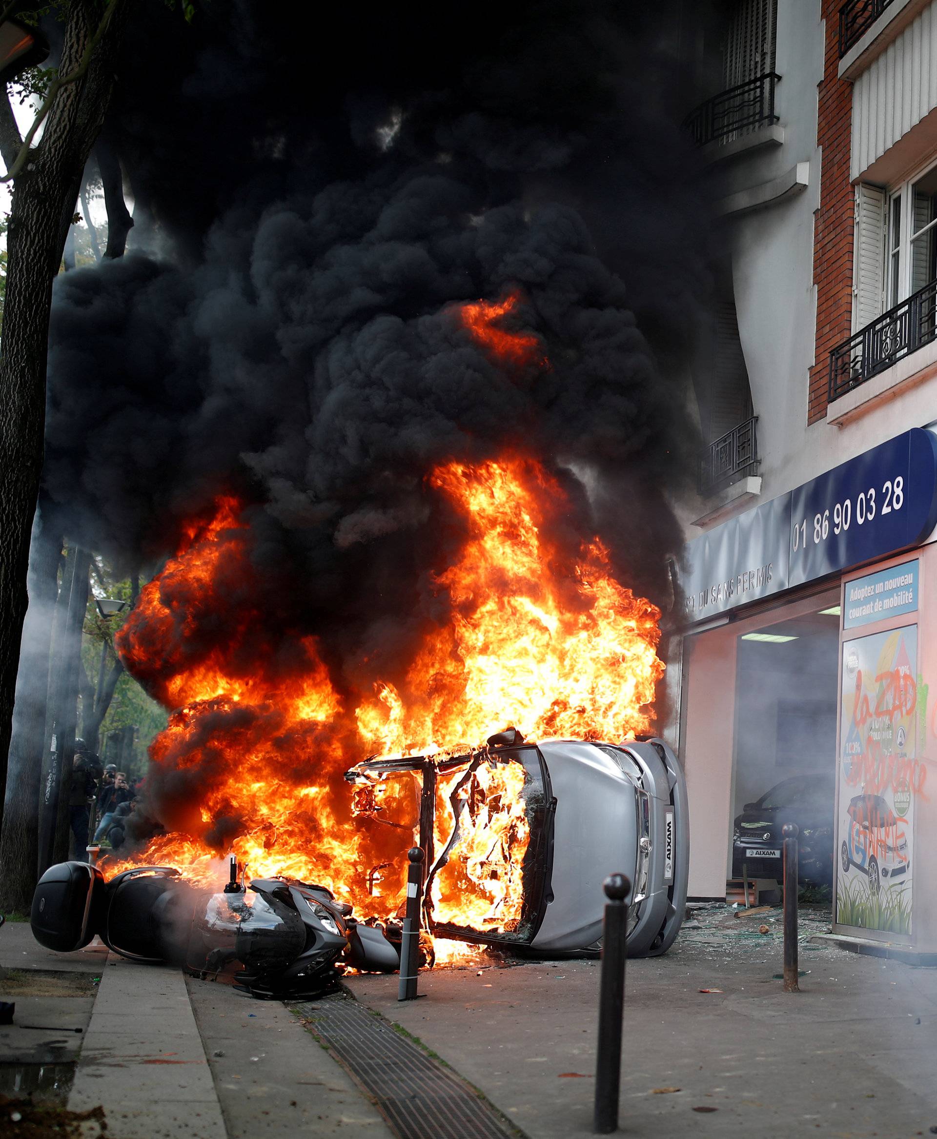 Car burns outside Renault automobile garage during May Day clashes in Paris