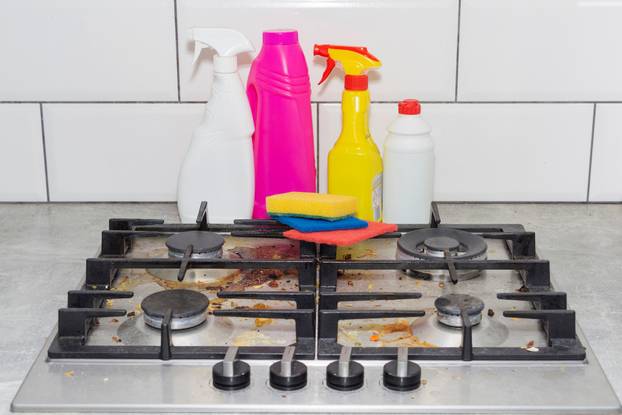 Dirty, top of the gas stove with bits of food. House cleaning.