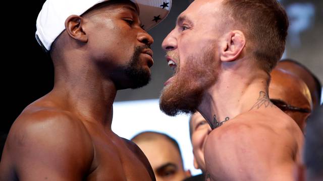 Undefeated boxer Floyd Mayweather Jr. (L) of the U.S. and UFC lightweight champion Conor McGregor of Ireland face off during their official weigh-in at T-Mobile Arena in Las Vegas