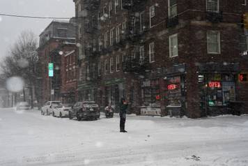 A pedestrian uses his mobile phone to photograph snowfall, in Brooklyn