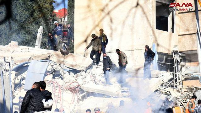 People inspect the damage at the site of a strike in the Mazzeh neighborhood of Damascus