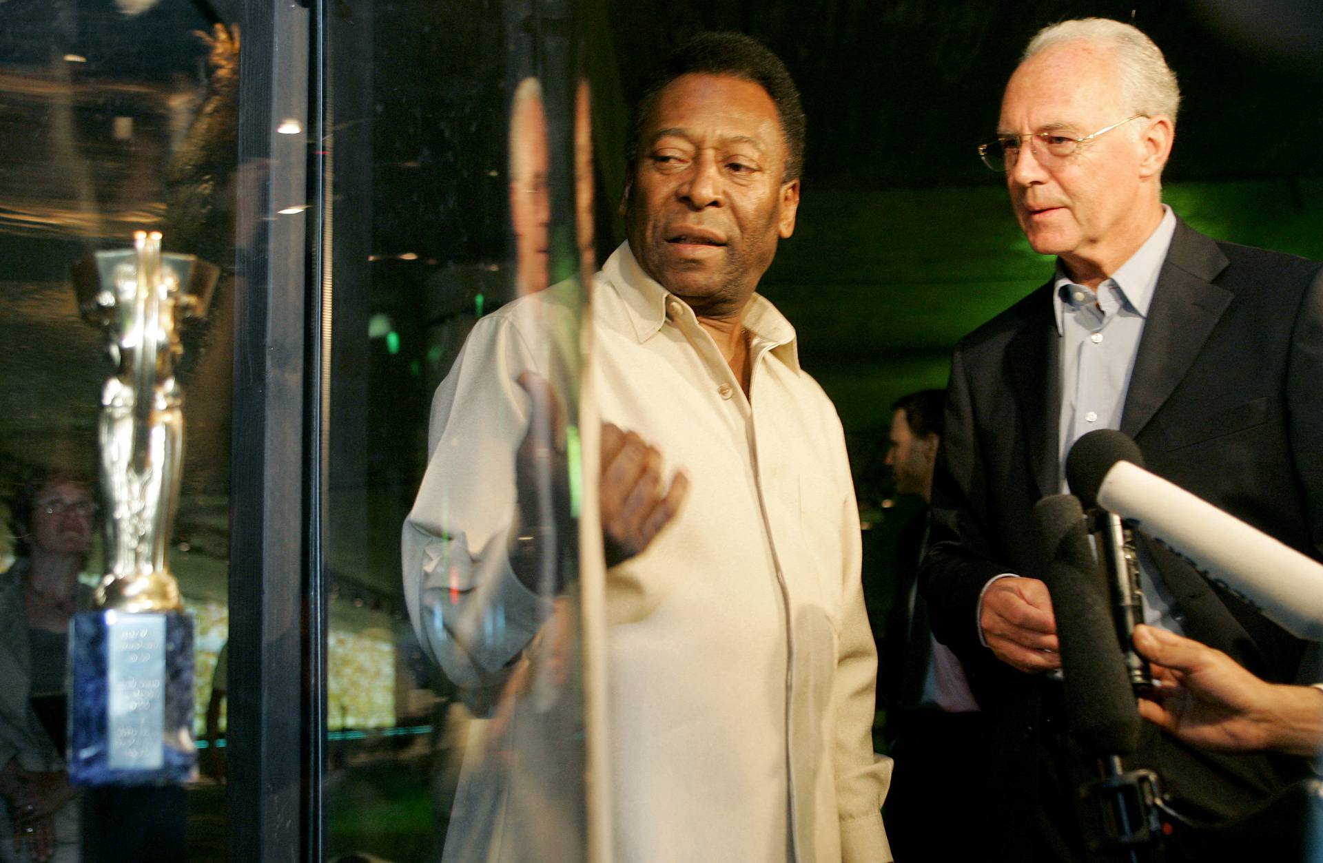 FILE PHOTO: Soccer legend Pele of Brazil and German player Beckenbauer stand beside a replica of the first World Cup trophy Coupe Jule Rimet during their visit to the exhibition 'Pelestation' in Berlin