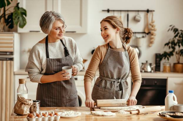 happy family grandmother  old mother mother-in-law and daughter-in-law daughter cook in kitchen, knead dough, bake cookies
