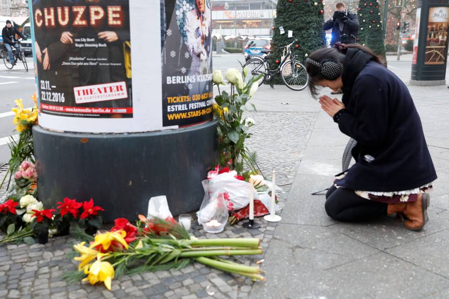 A woman prays near the area where a truck which ploughed into a crowded Christmas market in the German capital last night in Berlin