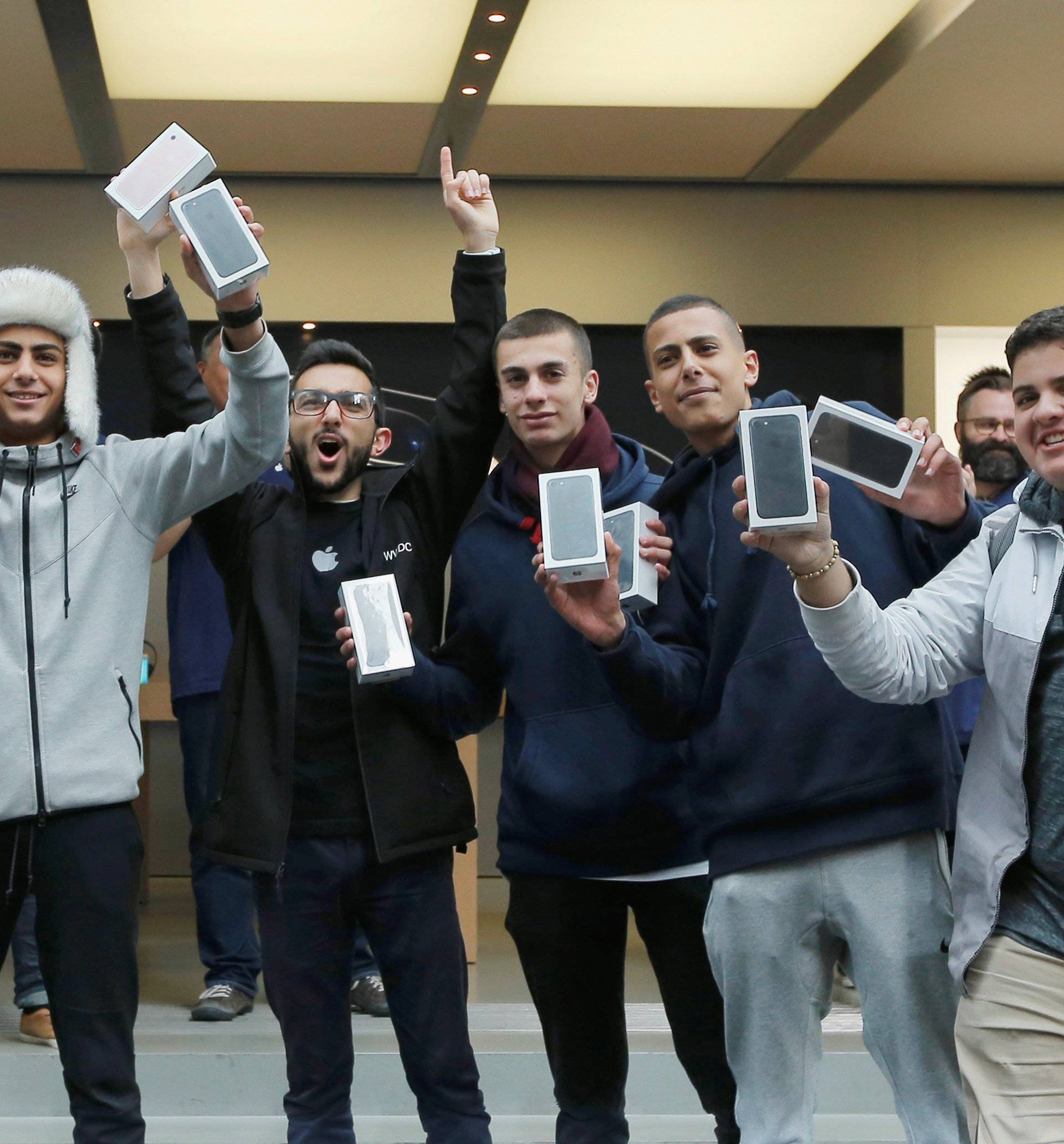 The first customers to walk out of Australia's flagship Apple store with the new iPhone 7 react for the press in Sydney