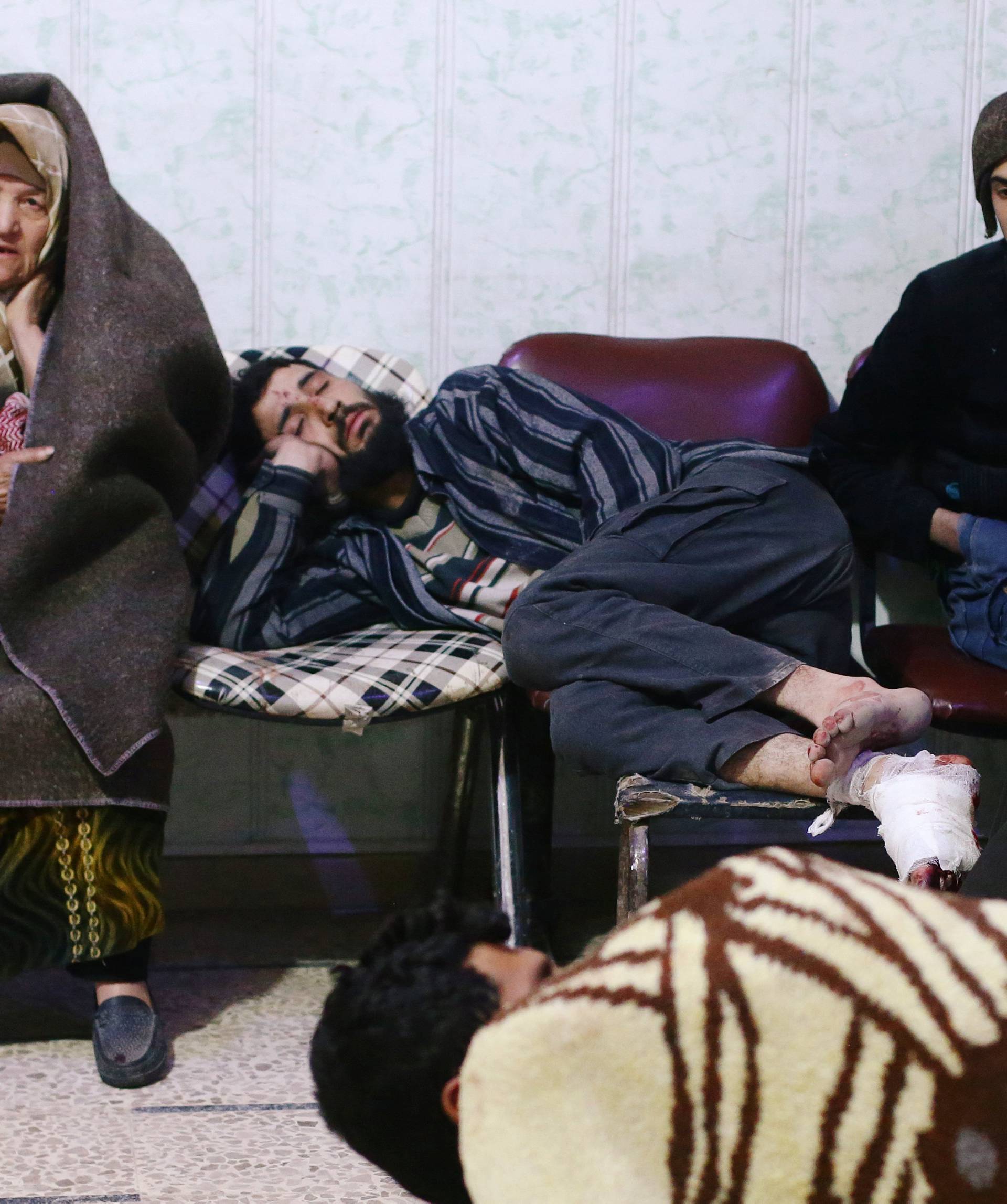 People sit at a medical point in the besieged town of Douma
