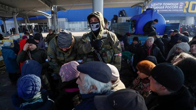 People stand in a line during the distribution of humanitarian aid in the besieged city of Mariupol