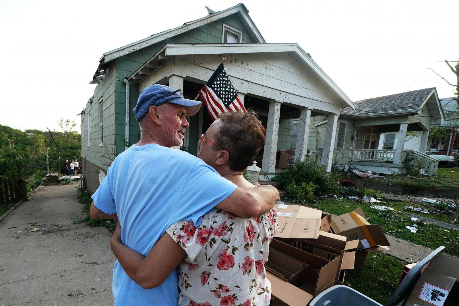 Gwen McGeorge hugs her husband in front of her home following a tornado in Jefferson City
