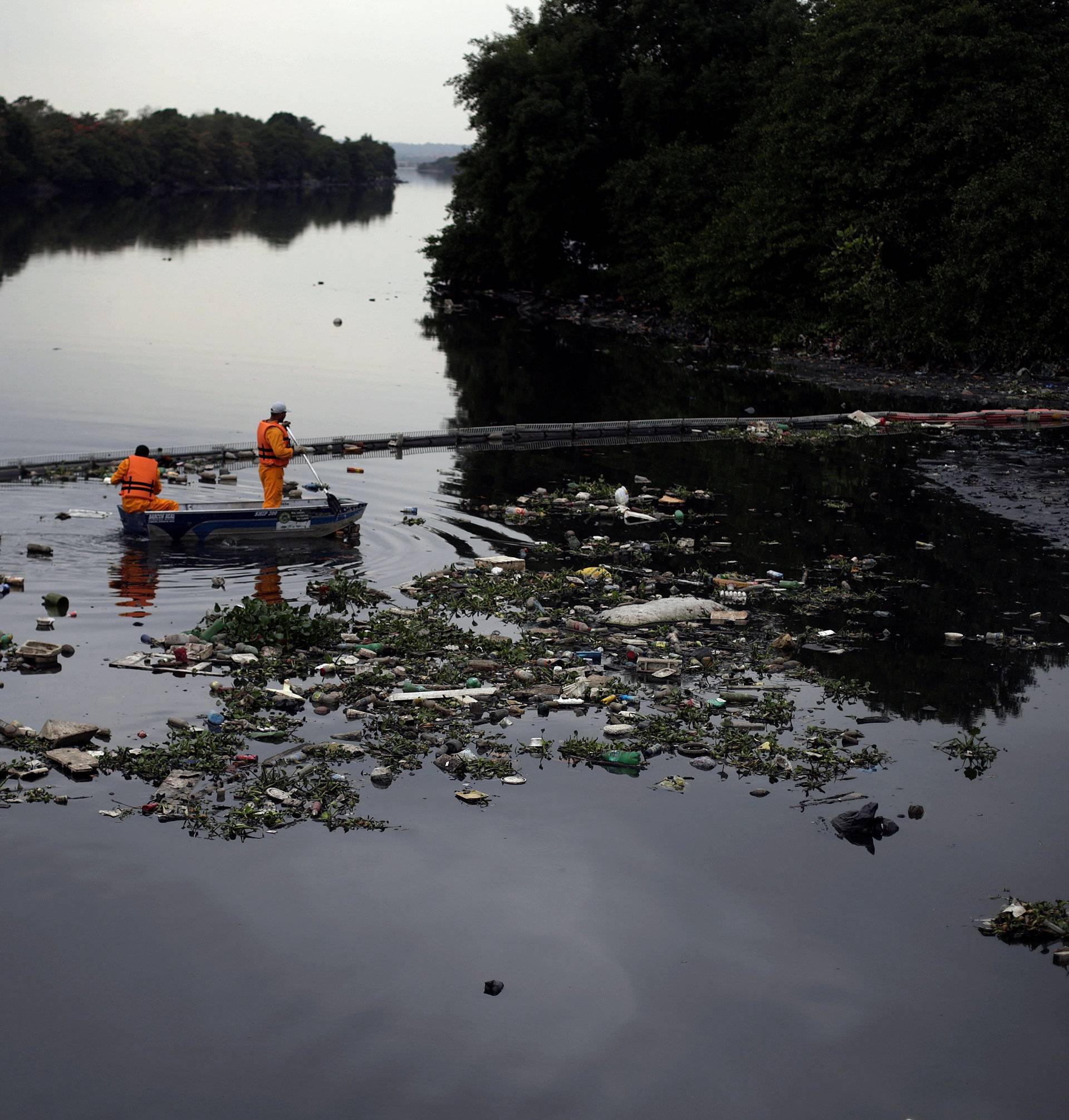 Men work cleaning up the garbage next to an ecobarrier at Meriti River which flows into Guanabara Bay, in Duque de Caxias, near Rio de Janeiro