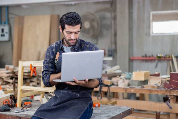 Young,Carpenter,Caucasian,Man,With,Laptop,Make,Drawing,On,Wood