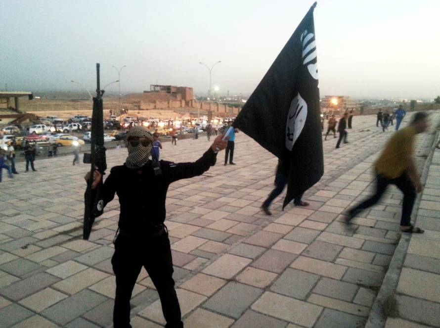 FILE PHOTO: ISIL fighter holds a flag and a weapon on a street in Mosul