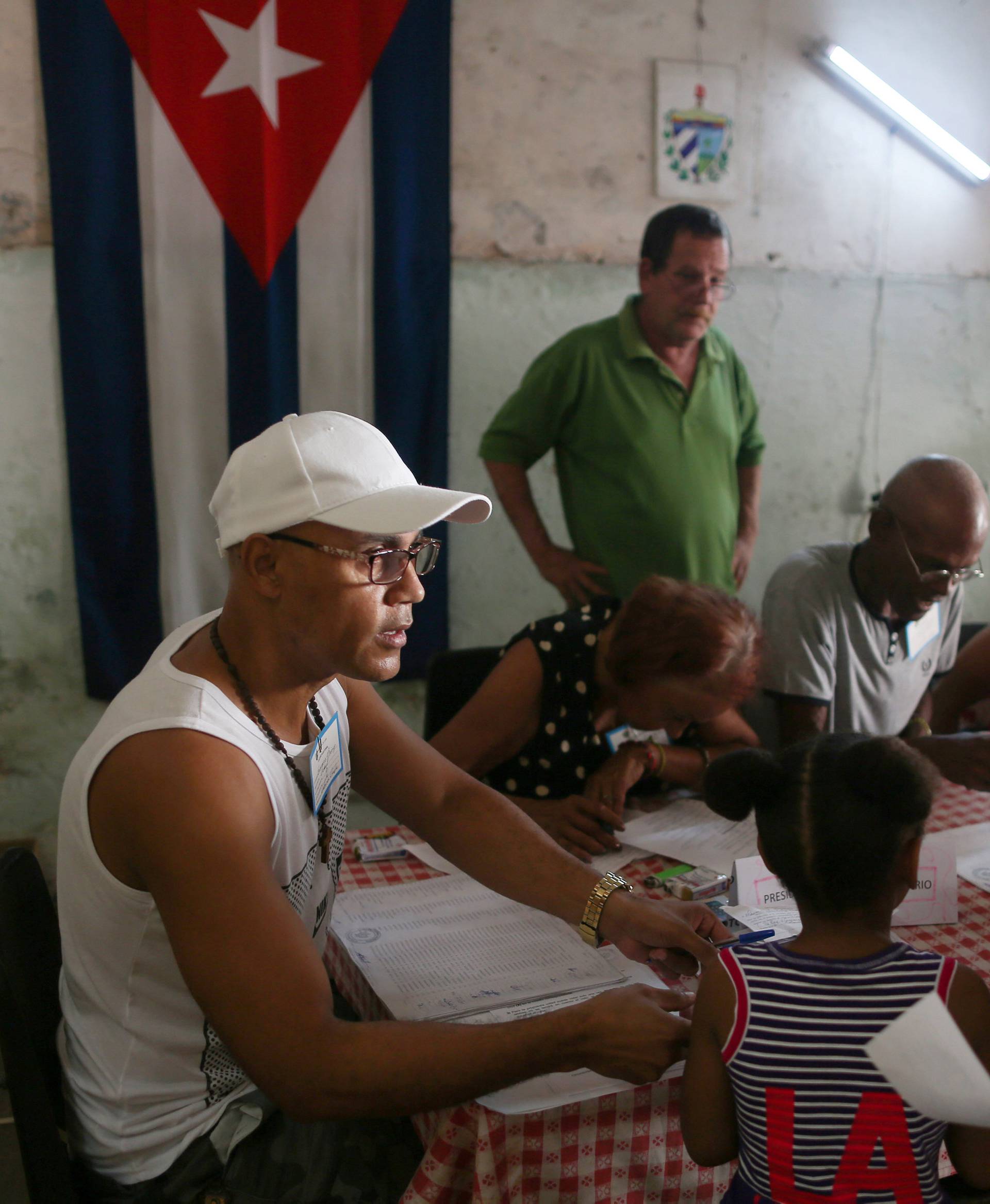 Election officials check the documents of a voter at a polling station during a constitutional referendum in Havana