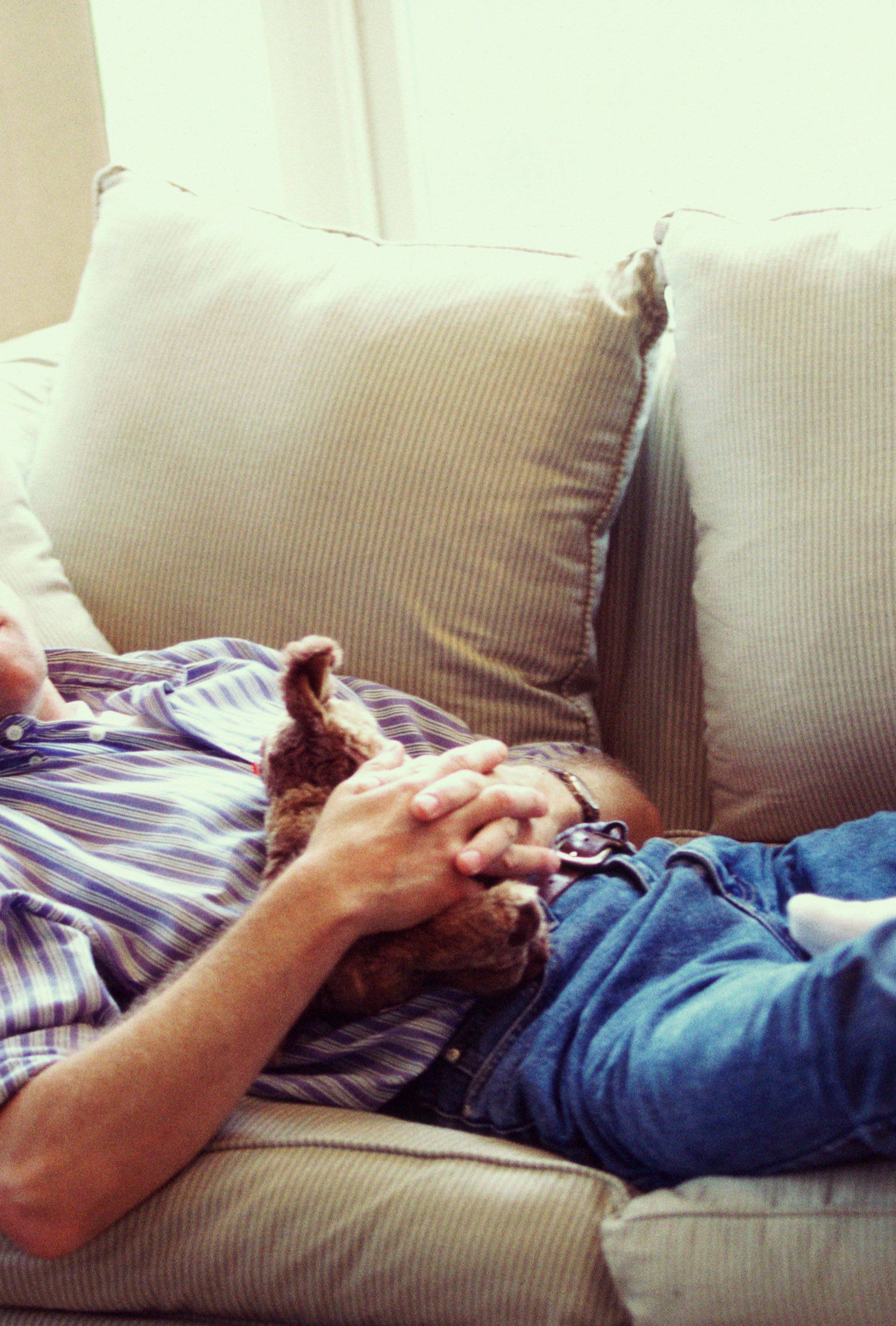 father asleep on sofa with son