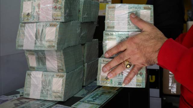 A money exchange vendor holds Lebanese pound banknotes at a shop in Beirut