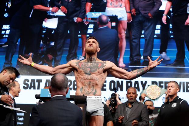 UFC lightweight champion Conor McGregor of Ireland poses on the scale during his official weigh-in at T-Mobile Arena in Las Vegas