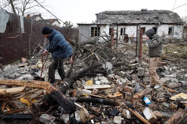 Local men walk at a site damaged during a Russian missile strike, in Kyiv