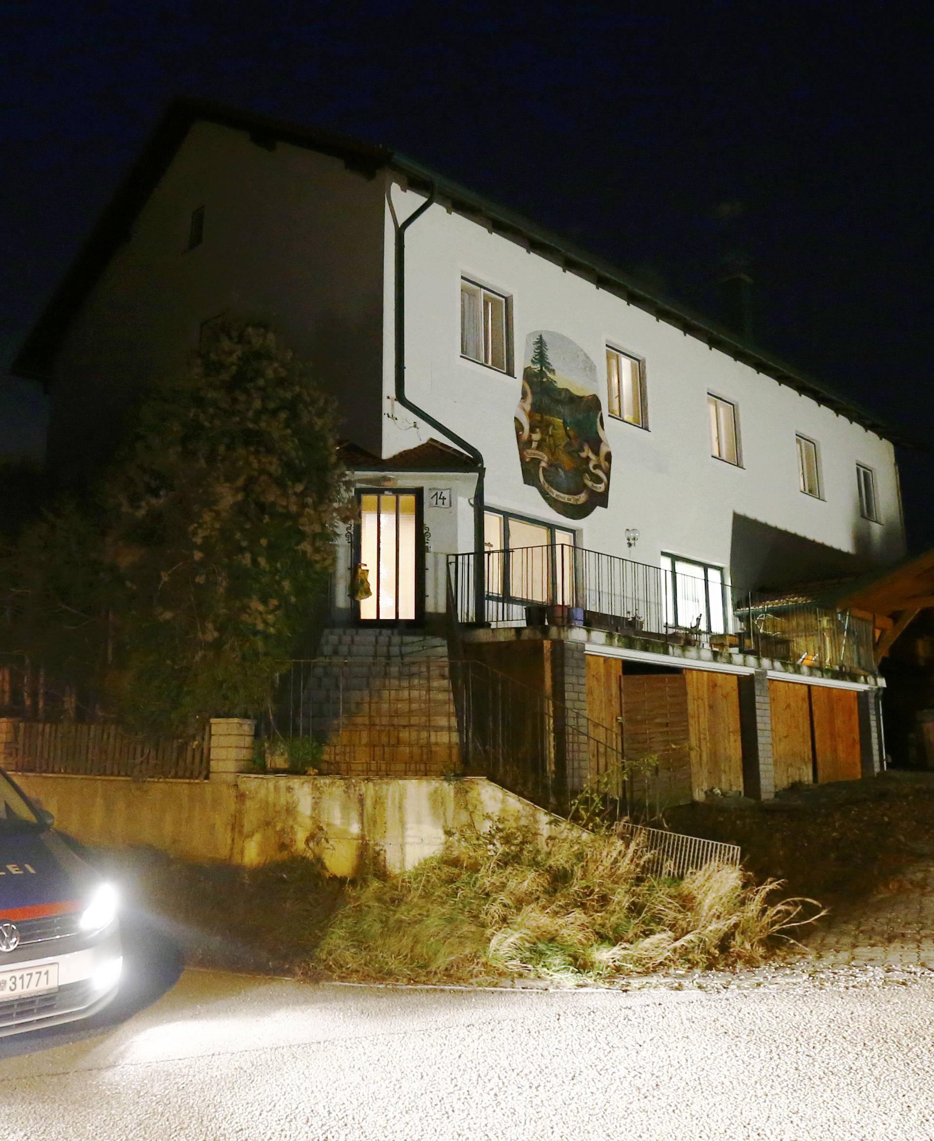 Police stand in front of a house where six people were found dead in Boeheimkirchen