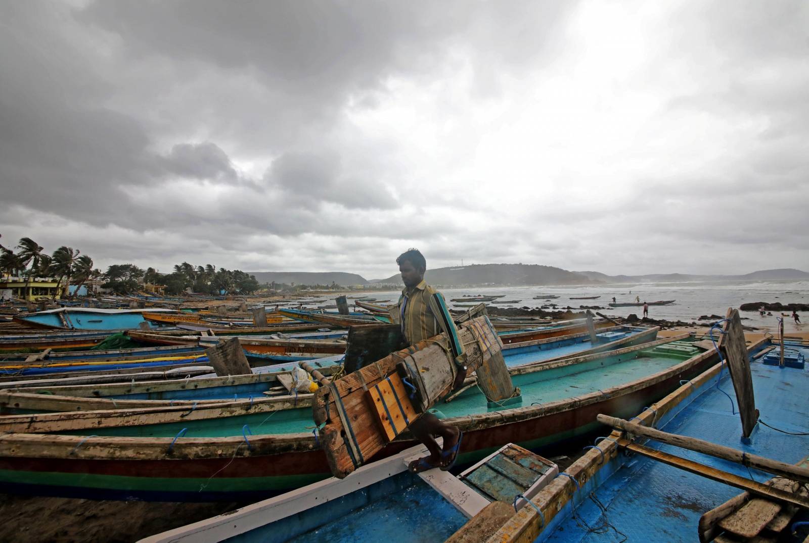 A fisherman carries his tools as he leaves for a safer place after tying his boats along the shore ahead of cyclone Fani in Peda Jalaripeta on the outskirts of Visakhapatnam