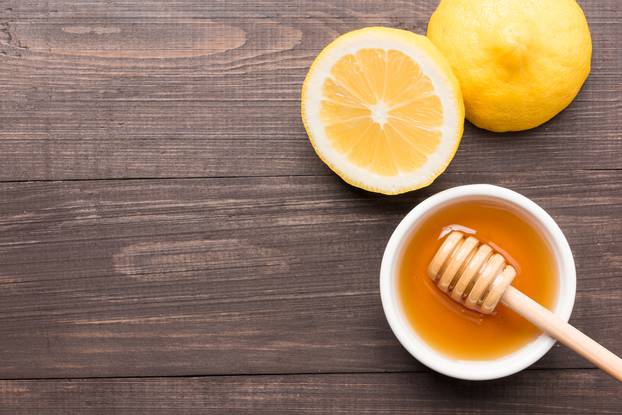 Bowl of sweet honey and lemons on wooden table