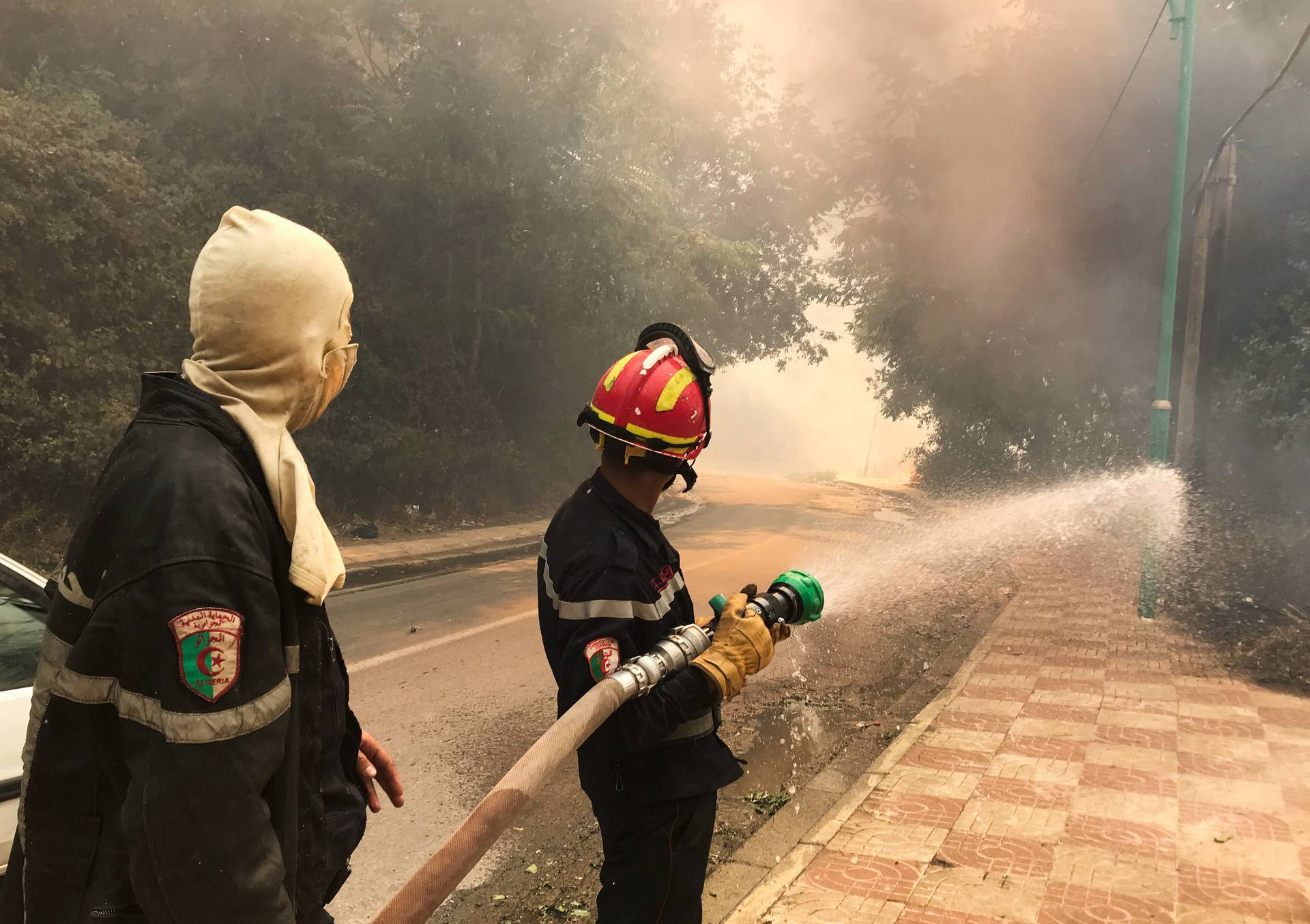 A firefighter uses a water hose during a forest fire in Ain al-Hammam village