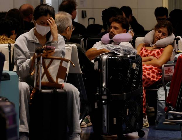Passengers rest at Haneda Airport as many flights are delayed and cancelled due to Typhoon Dujuan, in Tokyo