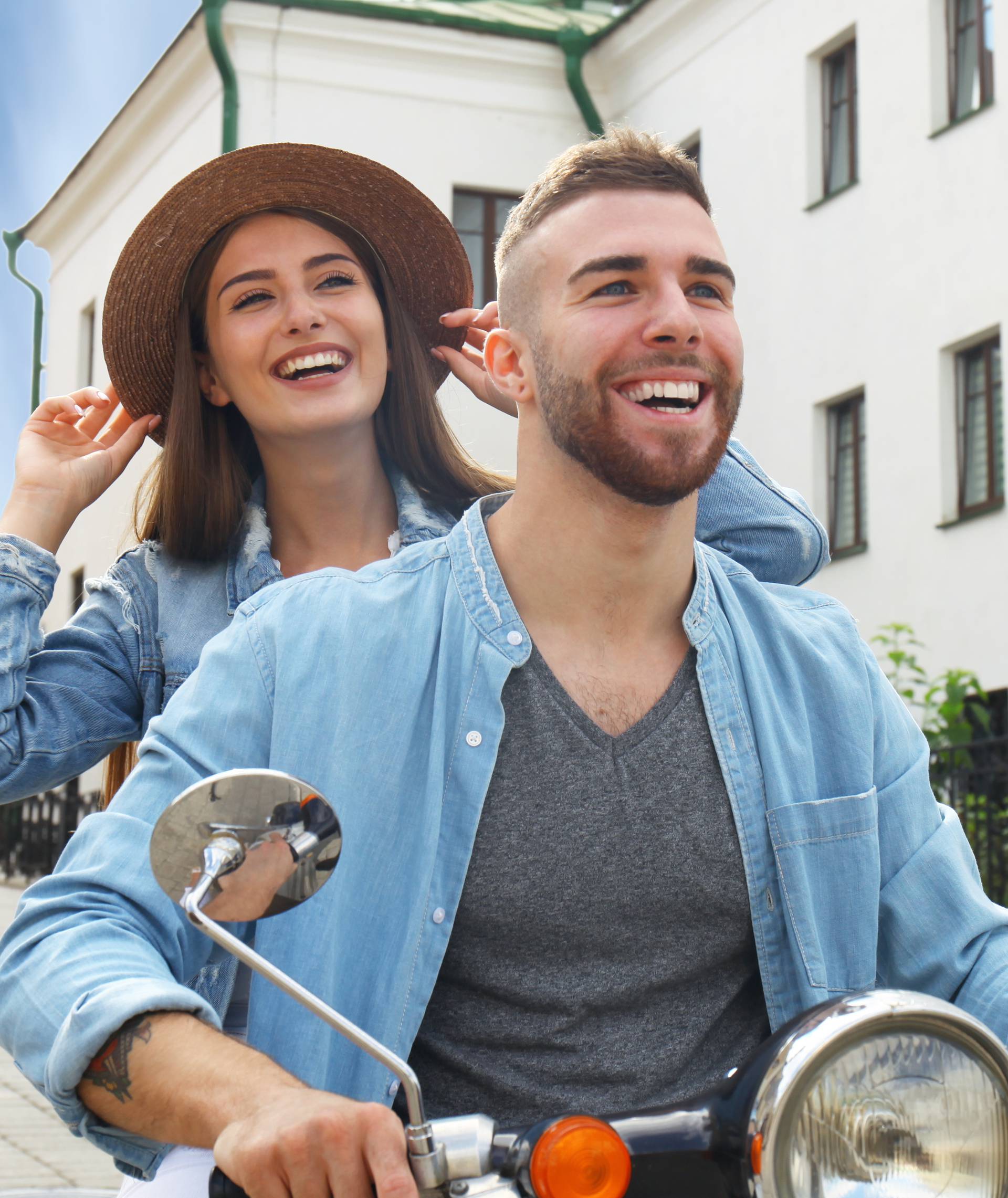 happy young couple riding scooter in town. Handsome guy and young woman travel. Adventure and vacations concept.