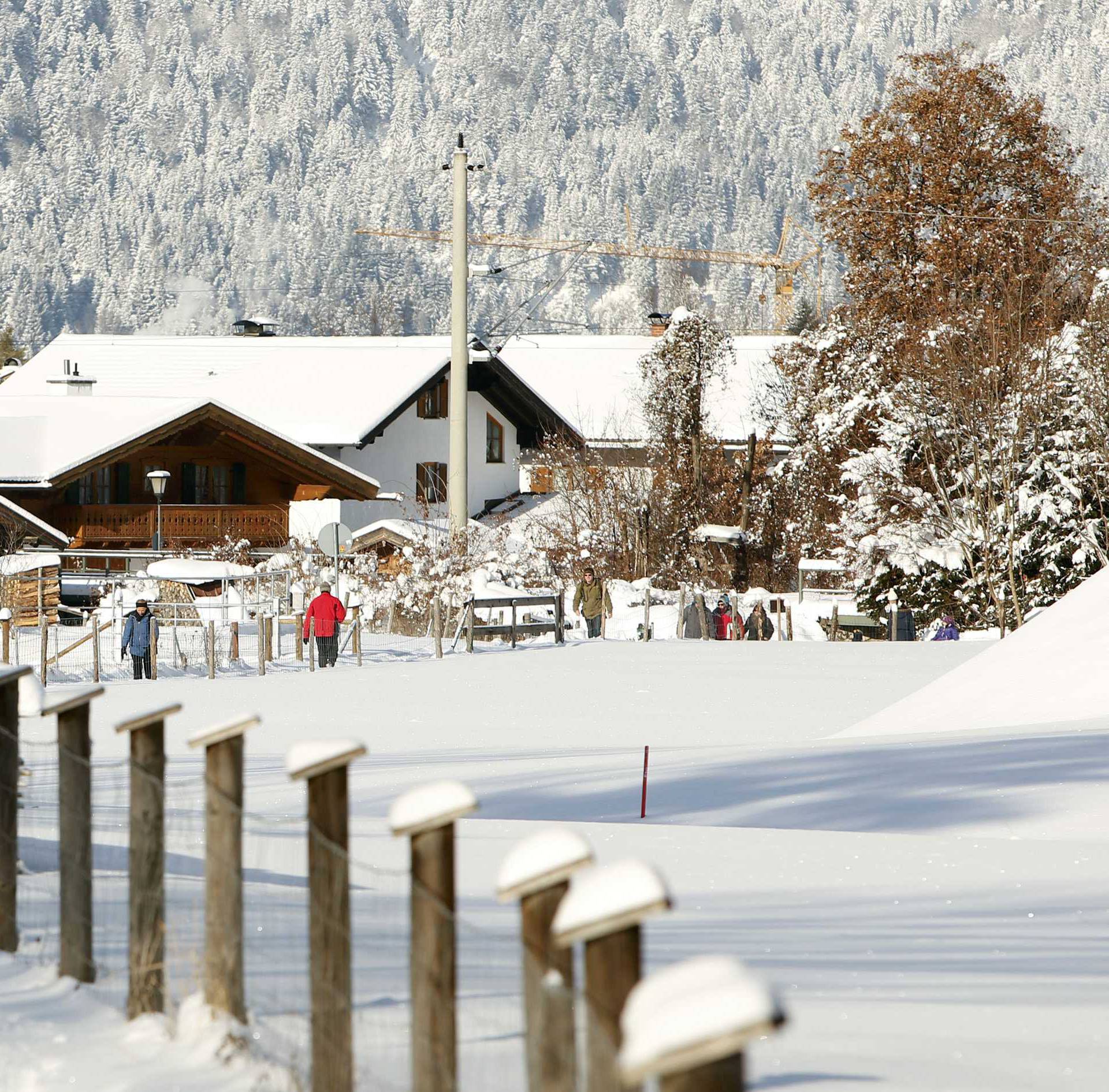 People walk through the snow during a sunny day in Garmisch-Partenkirchen