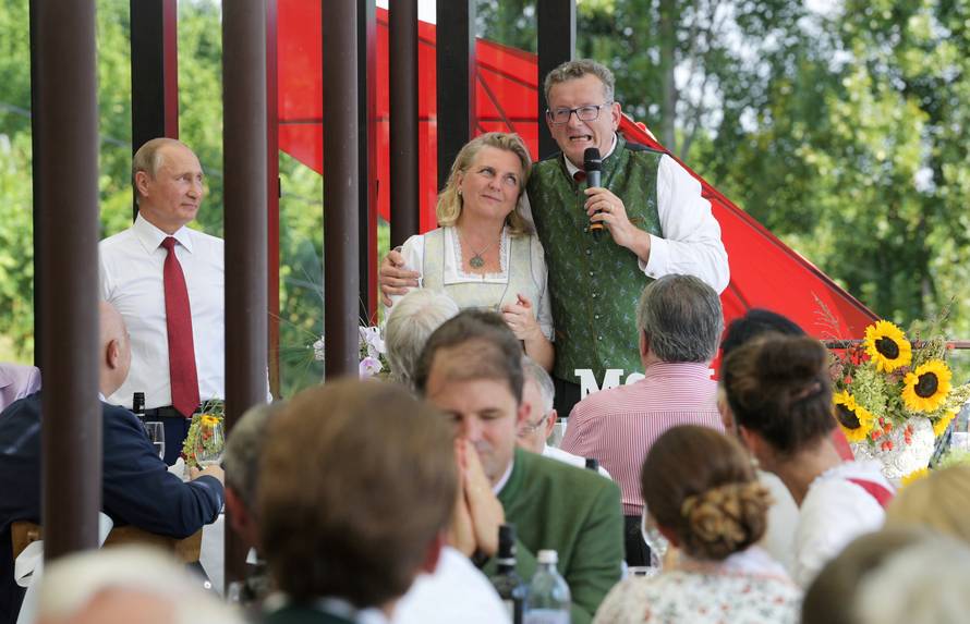Austria's FM Kneissl is embraced by her groom Meilinger during their wedding celebrations as Russia's President Putin looks on in Gamlitz