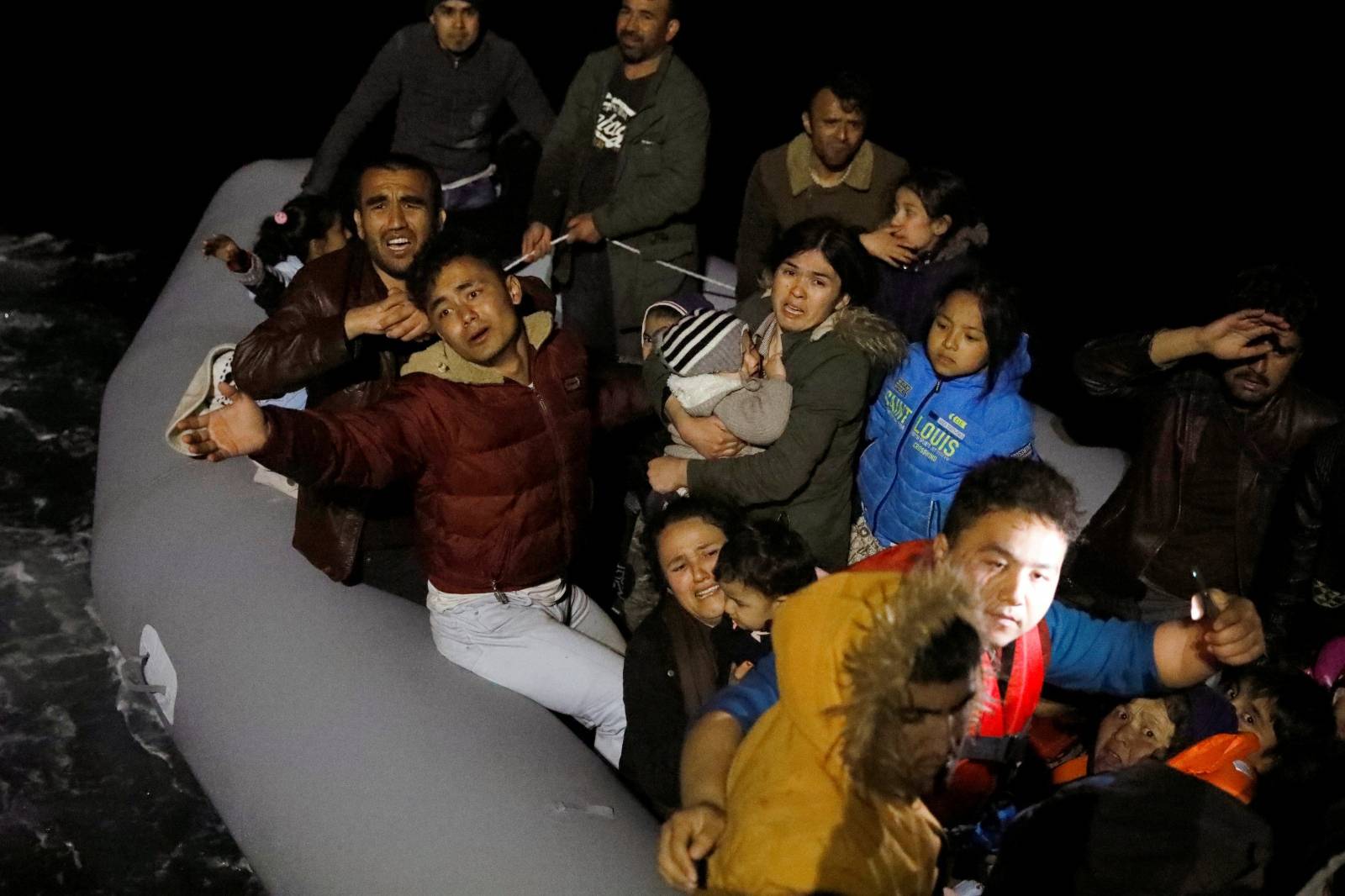 Migrants wave and shout for help, following a failed attempt to cross to the Greek island of Lesbos, as a Turkish Coast Guard boat aproaches them on the waters of the North Aegean Sea, off the shores of Canakkale