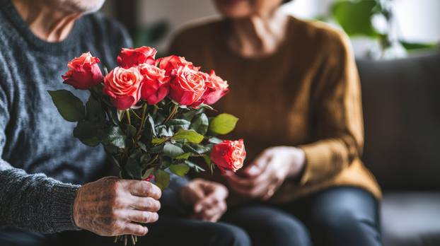 Elderly Asian Couple Sharing a Bouquet of Red Roses at Home. Concept of Love, Romance, and Togetherness in Senior Years. Valentine's Day, Anniversary