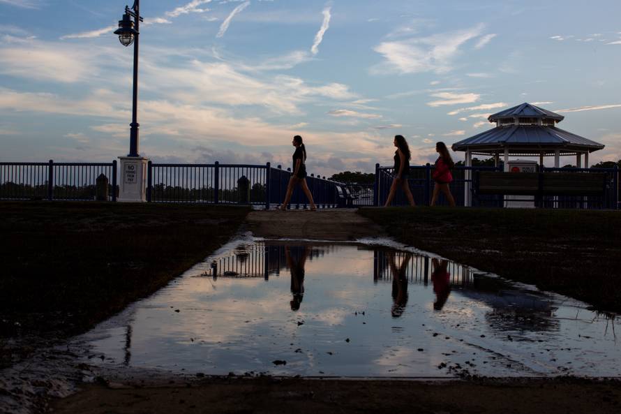 People walk along the walkboard during the sun set after the pass of Hurricane Florence, now downgraded to a tropical depression in Washington, North Carolina