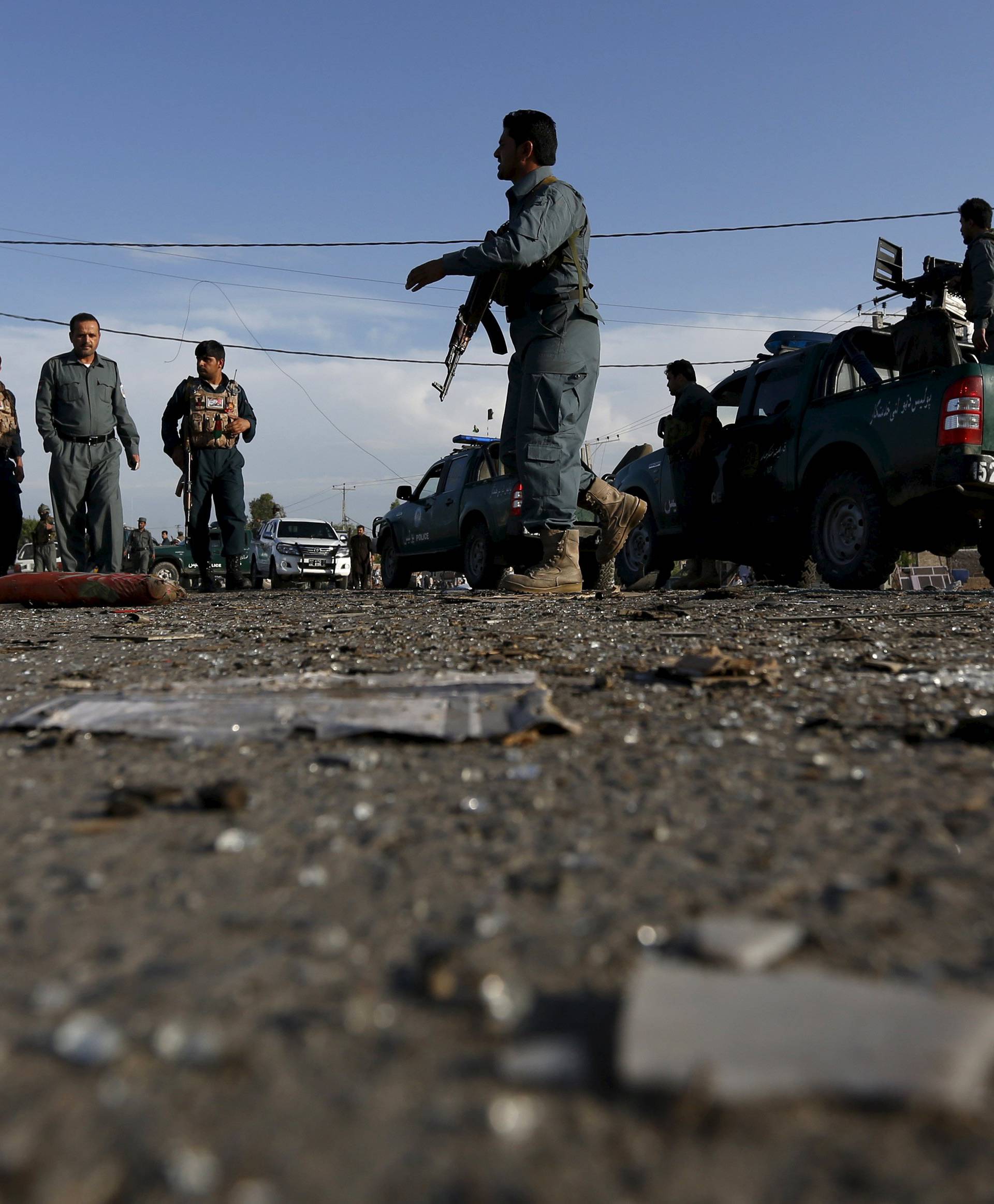 Afghan policemen inspect the site of a blast after a suicide attack in Jalalabad